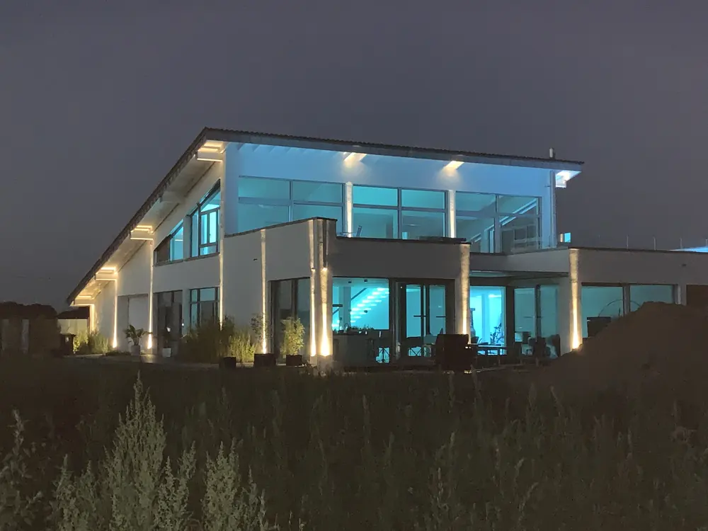 Beleuchtetes Wohnhaus am Abend, energetisch als Effizienzhaus ausgeführt