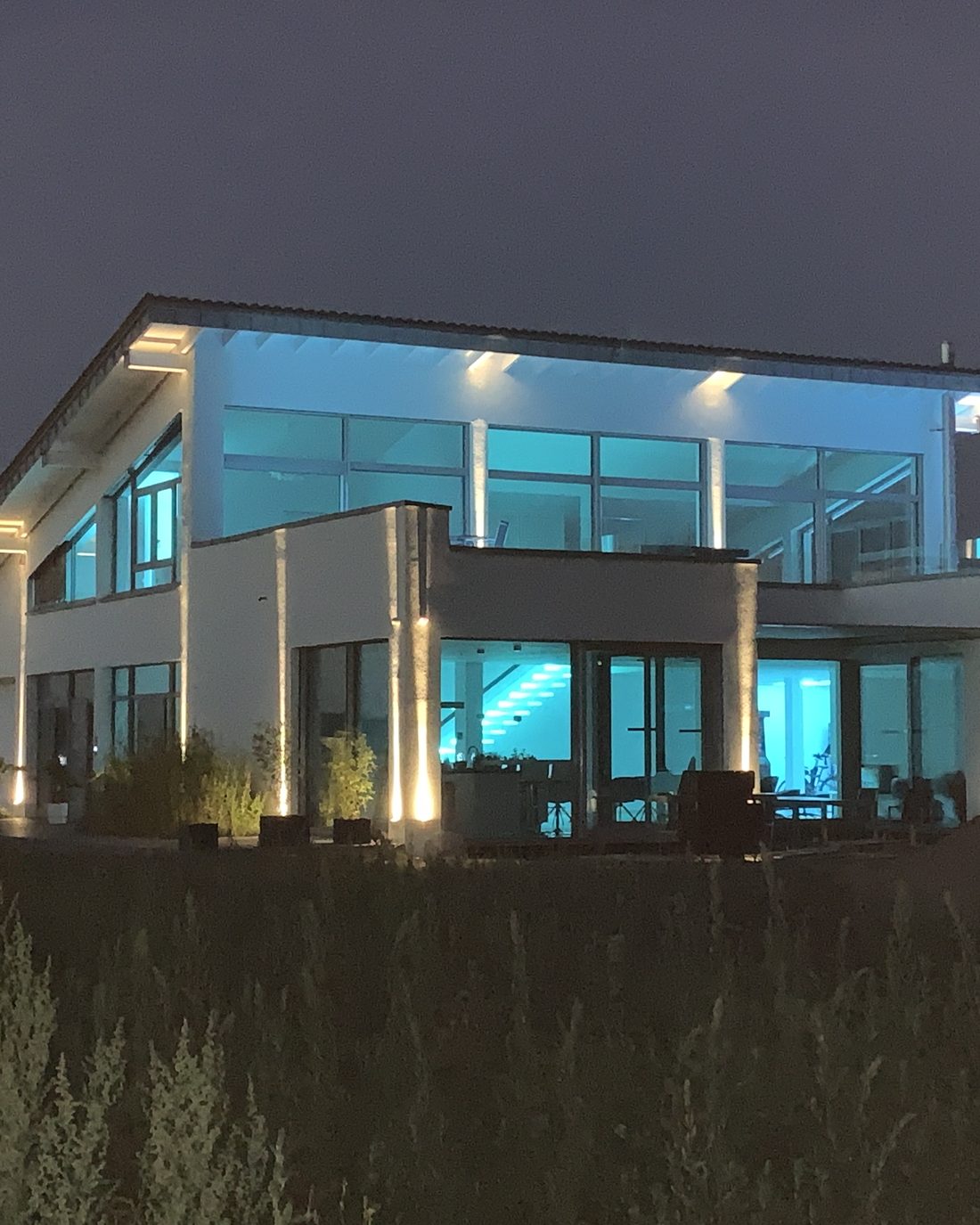 Beleuchtetes Einfamilienhaus in Meerbusch am Abend, energetisch als Effizienzhaus 55 mit Erdwärmepumpe ausgeführt