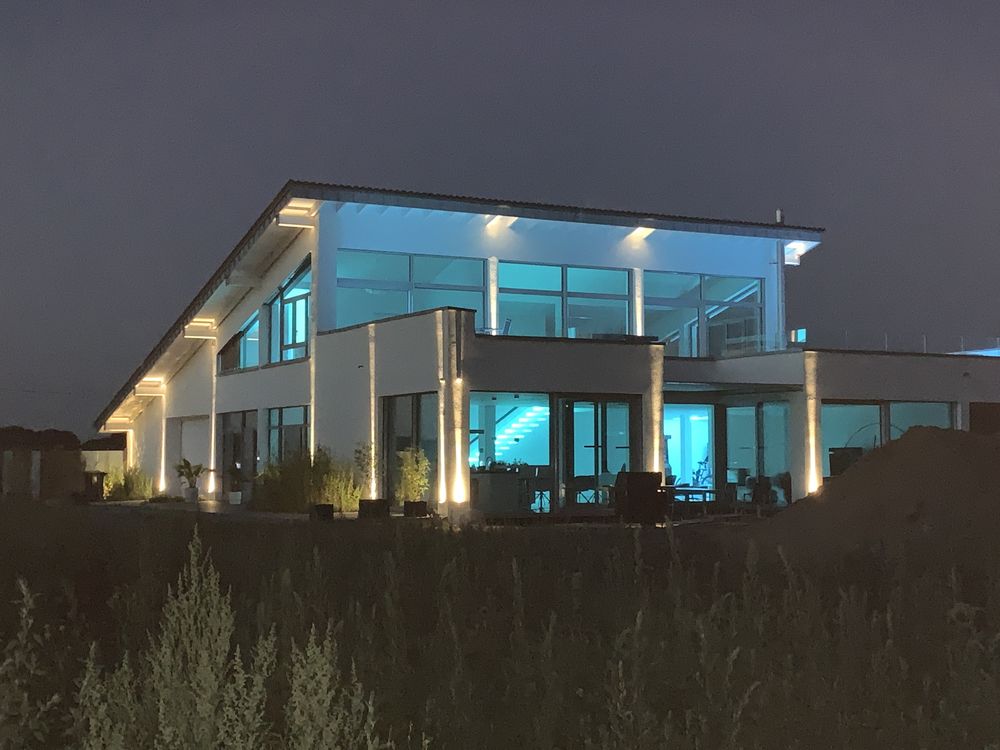 Beleuchtetes Einfamilienhaus in Meerbusch bei Nacht, Effizienzhaus 55 mit Erdwärmepumpe